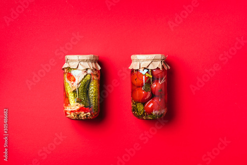 Canned and preserved vegetables in glass jars over yellow background. Top view. Flat lay. Copy space.
