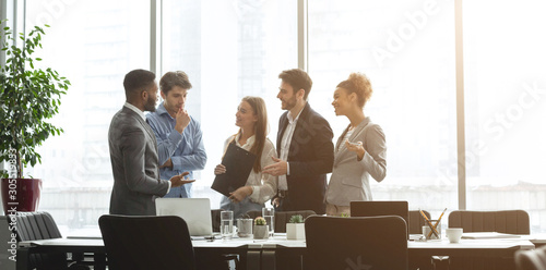 Successful business team talking against office windows