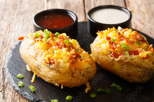 American food baked stuffed potatoes with cheddar cheese, green onions and bacon closeup. horizontal