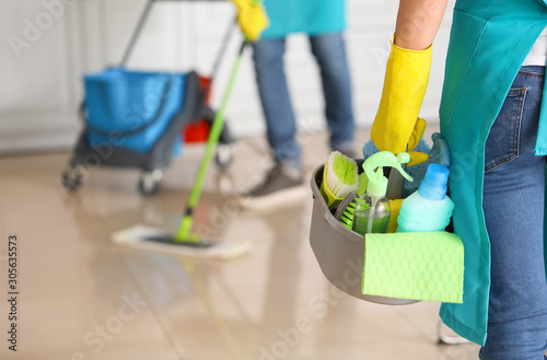 Female janitor with cleaning supplies in kitchen