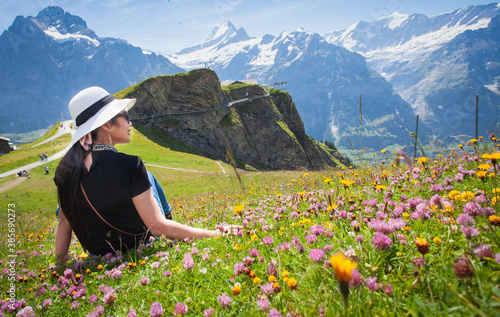 A picture of an Asian woman looking at a mountain view from a high angle in a colorful flower in Switzerland.