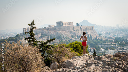 Teen in red shorts standing on hill with Parthenon in the background