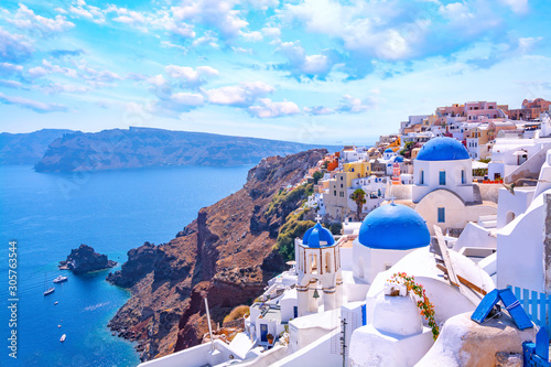 Piękny miasteczko Oia na wyspie Santorini, Grecja. Tradycyjna biała architektura i greckie cerkwie z niebieskimi kopułami nad kalderą na Morzu Egejskim. Malownicze tło podróży.