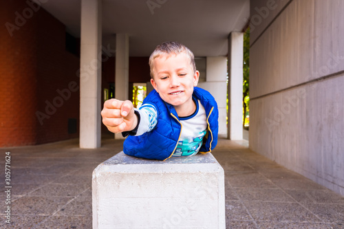 Brave boy with gesture of impetuousness and empowerment playing in the city.