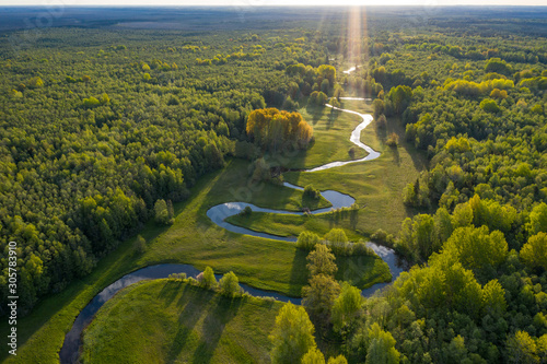 Forest in summer colors. Green deciduous trees and winding blue river in sunset. Mulgi meadow, Estonia, Europe