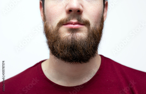 Portrait youn man with messy brown orange beard and moustache and messy hair. Bearded hipster on isolated white background with red shirt on.