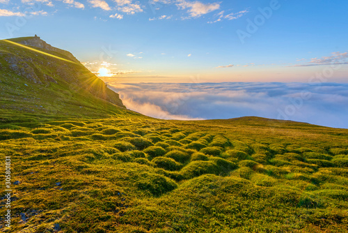 The midnight sun in the Northern cape of Soroya Island in Norwegian Finnmark, the Kjottvikvarden hill is at left. Fascinating sea of clouds is covering the Arctic Ocean surface at the background.