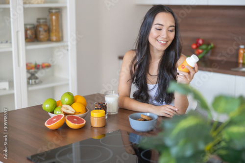 Young woman taking a nutritional supplement at breakfast