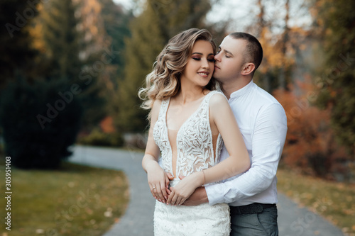 Loving couple in stylish wear hugs in the park in the autumn season. Autumn. Golden autumn. Golden leaves. Portrait of happy young couple outdoor