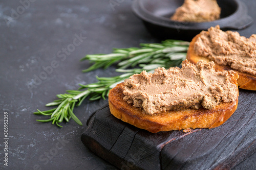 homemade meat pate on toasted crusty bread. dark photo style.