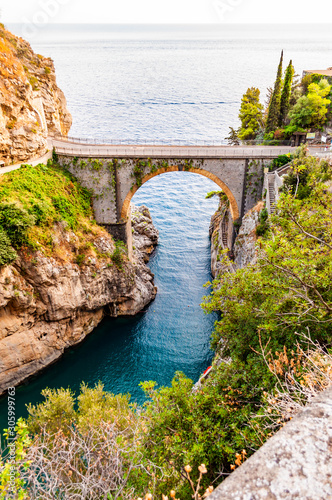 View on Fiordo di Furore arc bridge built between high rocky cliffs above the Tyrrhenian sea bay in Campania region. Unique cove under the cliffs, natural gorge, canyon or fiord