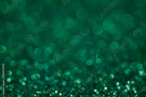 Abstract New Year emerald bokeh background with shining defocus sparkles. Blurred glitters shimmering dust macro close up, copy space for text logo