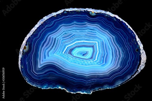 Slice of blue agate stone specimen, with rings of different blue shades, against a black limbo background