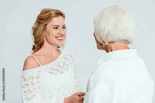 back view of mother looking at smiling daughter isolated on grey