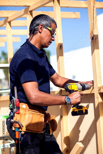 Handyman with toolsbelt and yellow drill in his hands.