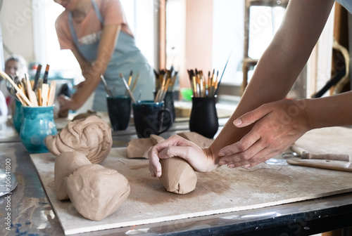 A Potter girl kneads a piece of clay with her hands in her Studio workshop.