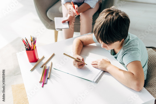 high angle view of kid with dyslexia drawing on paper with pencil