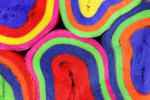 Close up coils of colorful crepe paper bunting of red, orange, yellow, green, blue and pink to make an abstract background