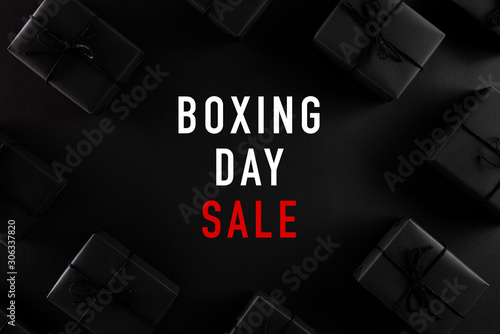 Top view of Boxing day Sale text with black gift box on dark background. Shopping concept boxing day and black Friday composition.