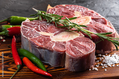 Meat beef veal shank sliced meat on dark wooden cutting board.