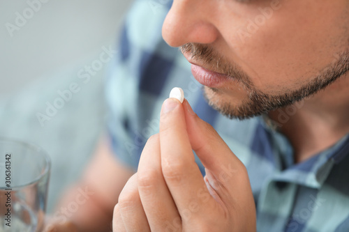 Man taking medicine at home, closeup