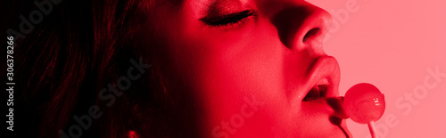 panoramic shot of attractive sexy girl eating lollipop in red light