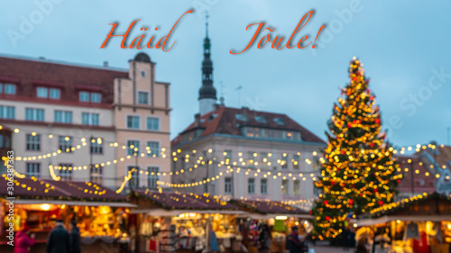Merry Christmas and New Year wishes in Estonian. Blurred background of the main square of old Tallinn city with a beautiful Christmas market and decorated fir tree. Happy New year 2020. Illuminated. 
