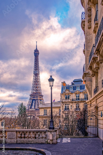 Paris, France - November 24, 2019: Small paris street with view on the famous paris eiffel tower on a cloudy day with some sunshine