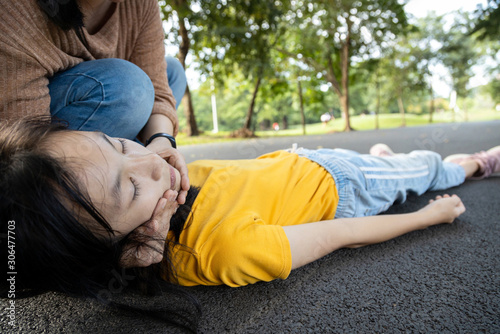 Sick teen daughter is fainted and fallen on floor while playing at park,asian mother help,take care,child girl with congestive heart failure,female unconscious lying down on ground suffer heart attack