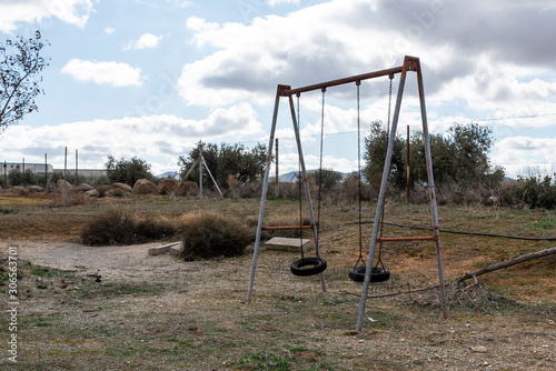 Columpio viejo, oxidado de neumáticos en parque abandonado.