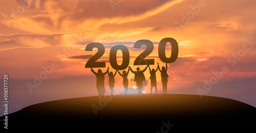 Happy new year 2020, Silhouette of 2020 letters on the mountain with business people raised arms in teamwork concept at sunrise.