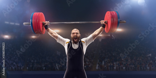 Male athlete is lifting a barbell on a professional stadium. Stadium and crowd are made in 3d.