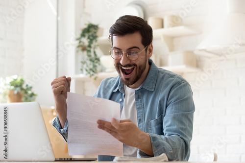 Excited man reading postal mail letter overjoyed by good news