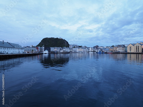 Calm secessionist houses of european Alesund town reflected in water in Norway at blue hour