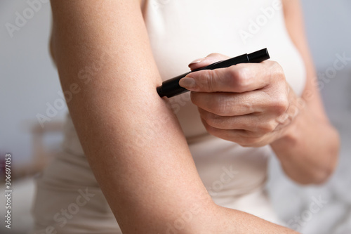 Aged diabetic woman using lancets check blood sugar level closeup