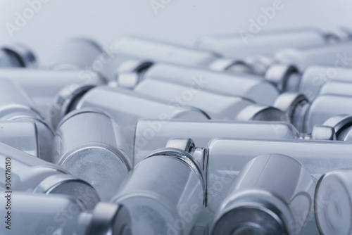 Glass medical ampoule vial for injection. Medicine is dry white drug penicillin powder or liquid with of aqueous solution in ampulla. Close up. Bottles ampule with aluminum cap on backgrounds gray.