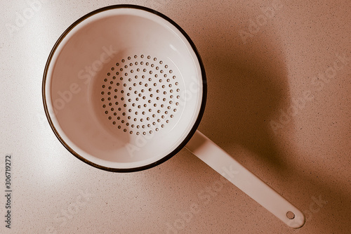 Kitchen tool colander with a handle on the table, top view.