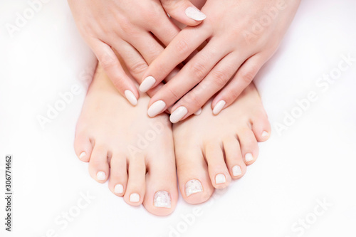 Closeup photo of female legs on a white towel in a spa salon on a pedicure and manicure procedure. nude colors.