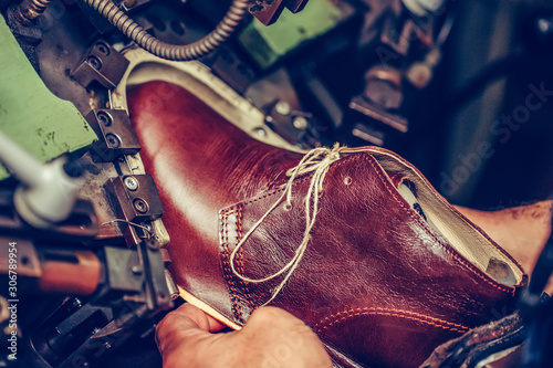 Experienced shoemaker using a special machine for putting shoes on the mold, in the footwear industry