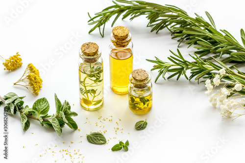 Aromatherapy. Essential oils in small bottles near fresh herbs on white background
