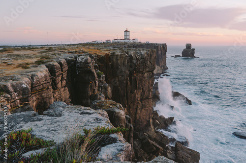 Lighthouse on the edge of a cliff big ocean waves crash on a rock Peniche Portugal