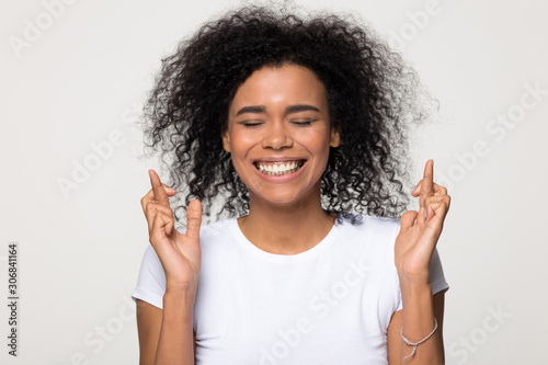 Smiling African American woman crossing fingers wishing good luck