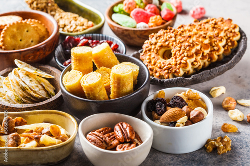 Variety of snacks and sweets on gray background. Waffles, nuts, sweets, cookies, chips and fruits.