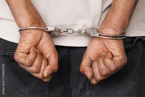 Close-up arrested hands african man handcuffed. Prisoner or arrested terrorist hands in handcuffs. 