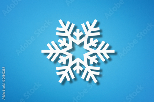 Snowflake shape made from cut paper on blue background
