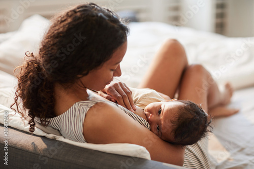 High angle portrait of young African-American mother breastfeeding cute baby boy with child looking at camera, copy space