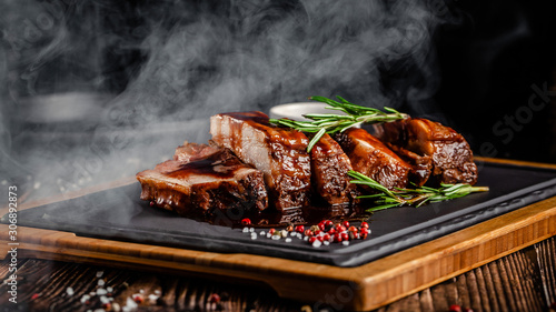 American food concept. Grilled pork ribs with grilled sauce, with smoke, spices and rosemary. Background image. copy space