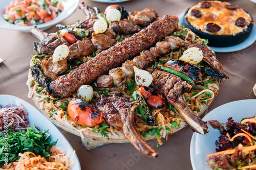 Traditional Turkish Adana kebab or kebap meat food, appetizers, raki and salgam on table from top view in turkish restaurant. 