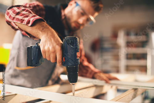 Young man working with drill in the workshop