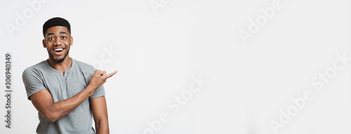 Excited african american guy pointing aside at empty space